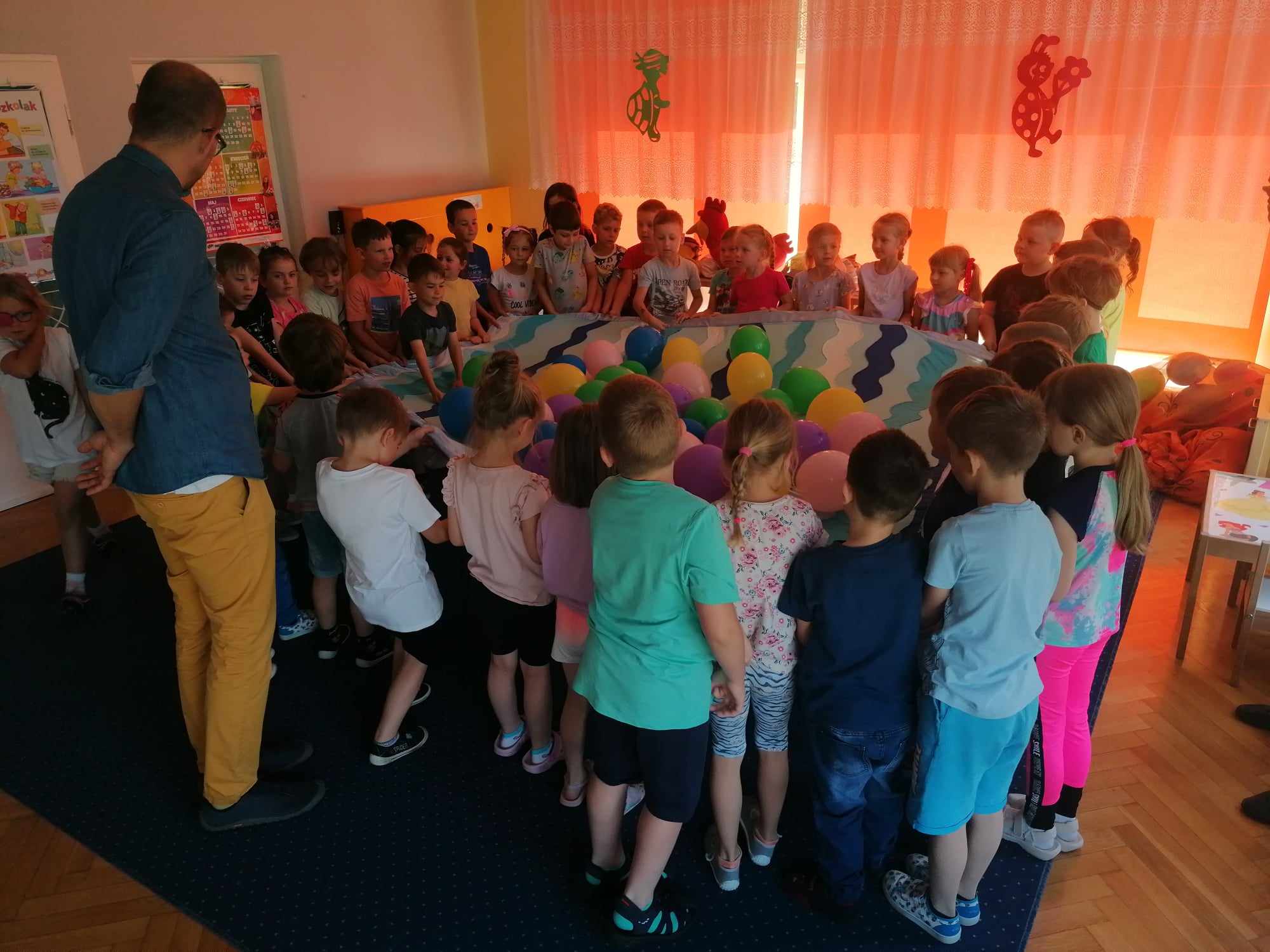 Grupa dzieci bawiąca się chustą animacyjną.